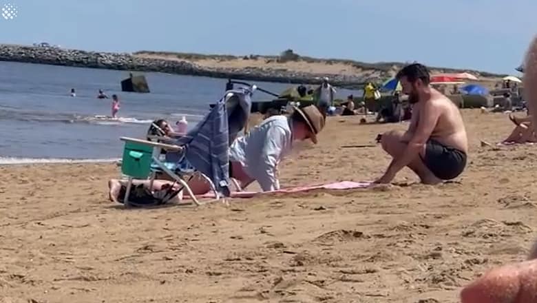 Thoughtful husband digs hole in beach so pregnant wife can lay down
