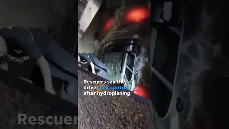 Driver rescued from hood of car after crashing into floodwaters #Shorts